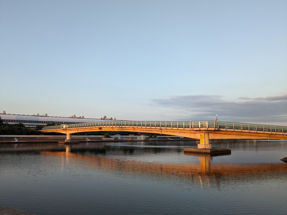 川にかかる橋。橋は朝日でオレンジ色に染まっている。水面は橋を写している