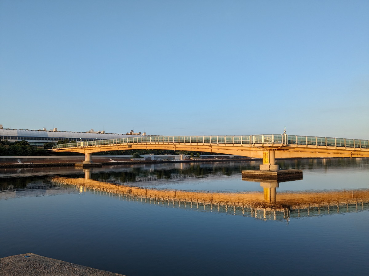 川にかかる橋。橋は朝日でオレンジ色に染まっている。水面は綺麗にそんな橋を写している