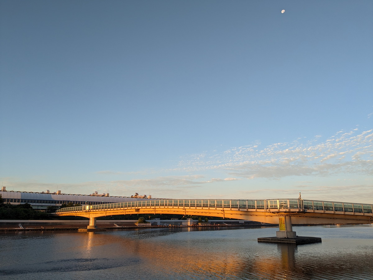 川に浮かぶ橋。橋は朝日に照られされている。空には月が浮かんでいる。