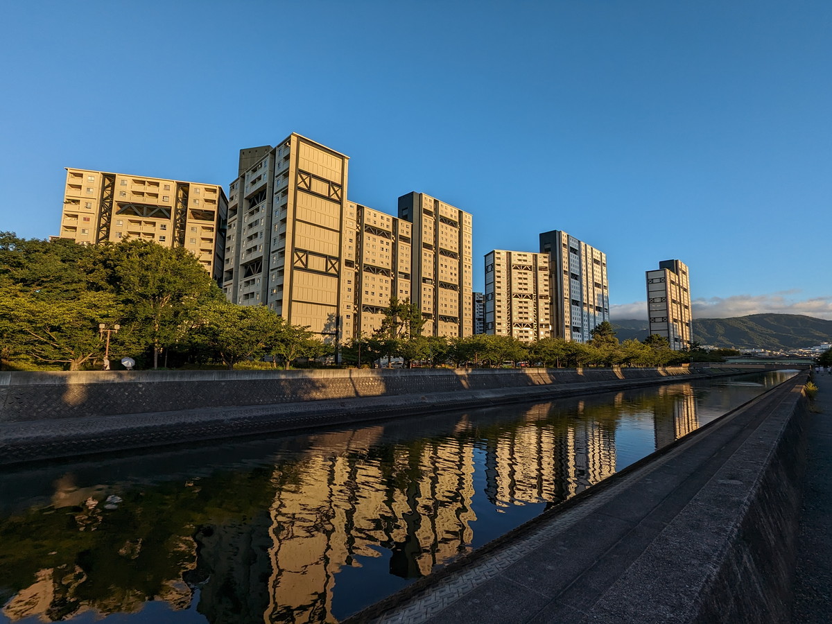 川沿いの高層住宅群が朝日に照らされている。