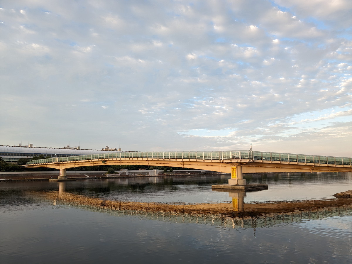 川の間にかかる橋。橋は朝日に照らされてオレンジ色に染まっている。